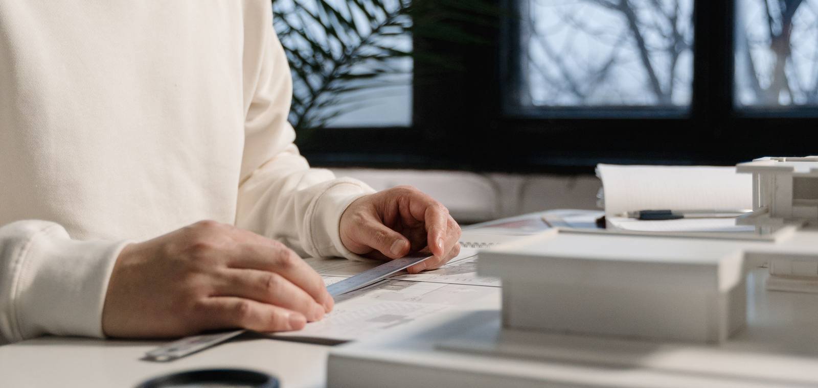 Hands going over documents on a desk, next to a window.